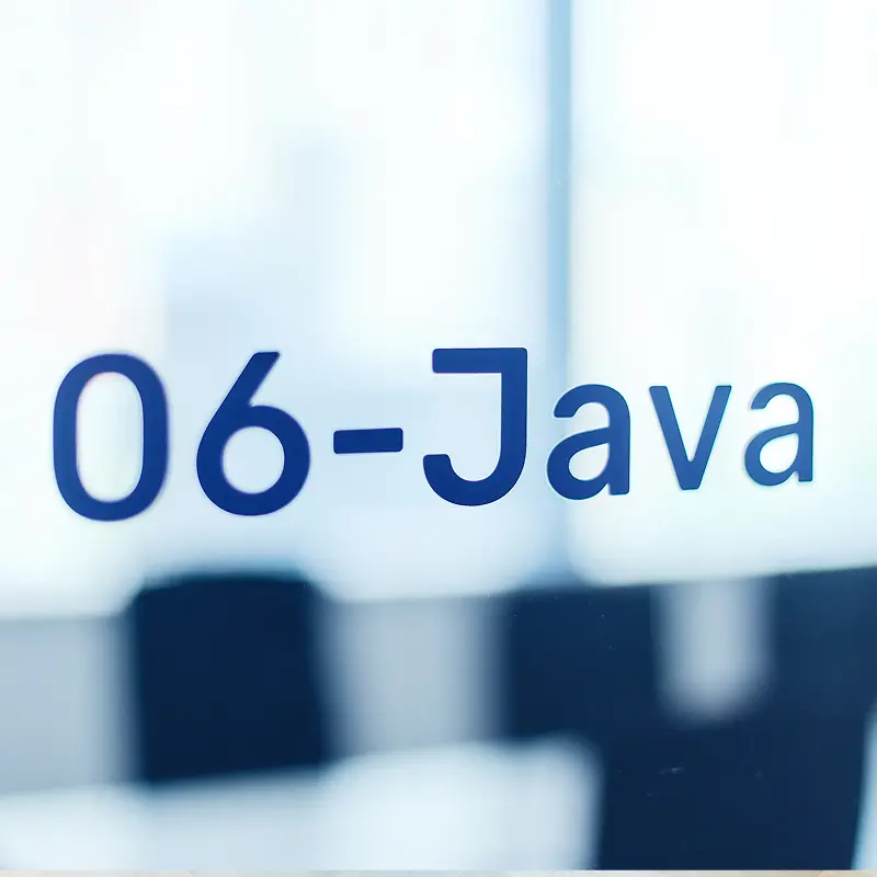 会議室のガラス扉に表示された「06-Java」の青い文字。ミーティングルームの部屋番号とテクノロジースタック表示