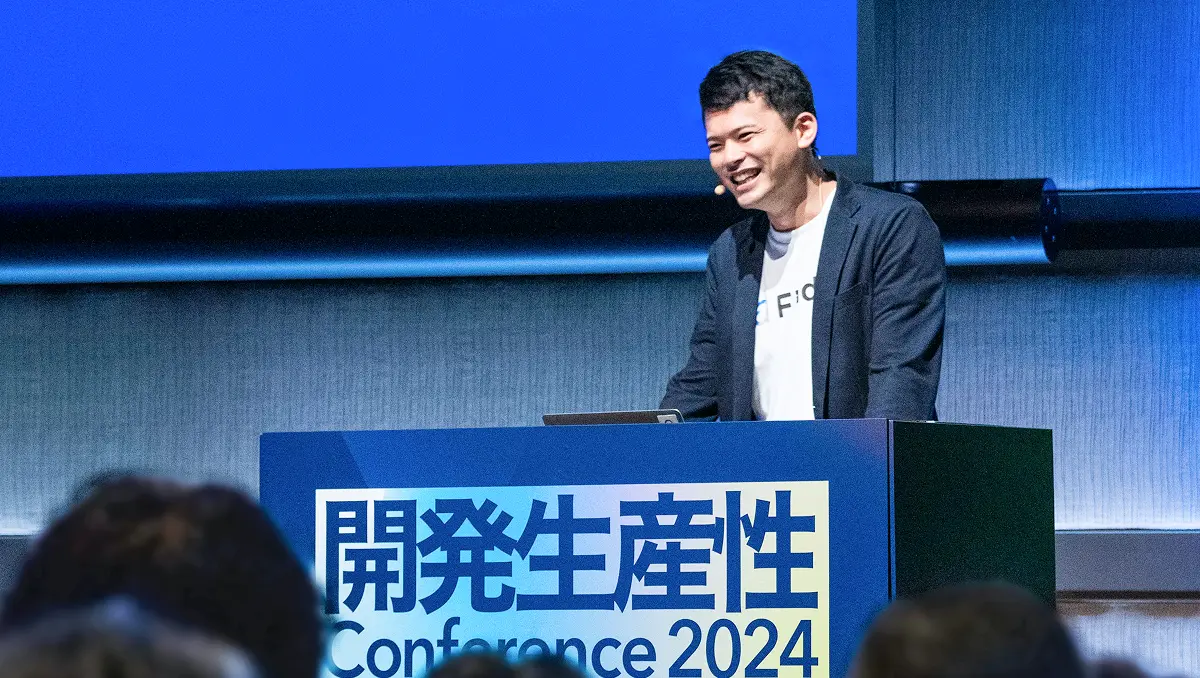 開発生産性カンファレンス2024の登壇シーンで、笑顔で講演するFindyのメンバー。ブルーを基調とした洗練された壇上デザイン