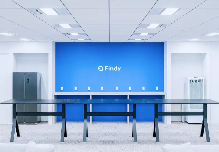 白を基調とした社内スペースに、ブルーの壁面とFindyのロゴが映えるモダンなミーティングテーブルエリア
